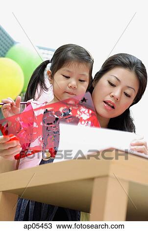 Stock Image - Mother with young daughter, using stencils. Fotosearch
