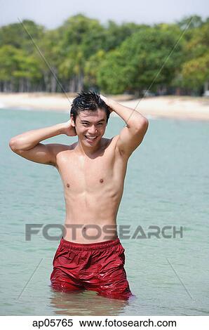 Stock Photography - One man standing in sea, hands on head. Fotosearch