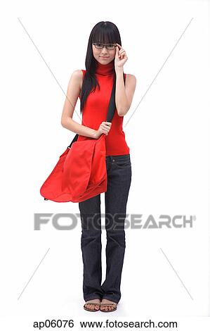 Stock Photograph - Portrait of a young woman with shoulder bag, adjusting glasses. Fotosearch