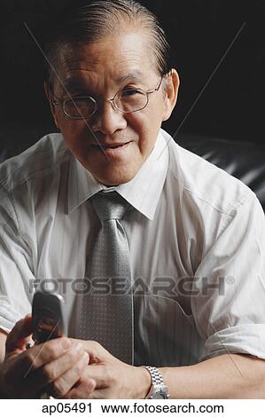 Stock Image - Senior businessman holding mobile phone. Fotosearch