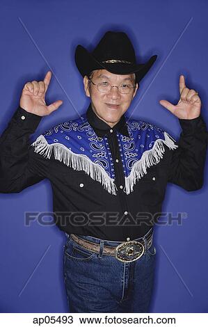 Stock Image - Senior man dressed in cowboy attire, making hand sign. Fotosearch