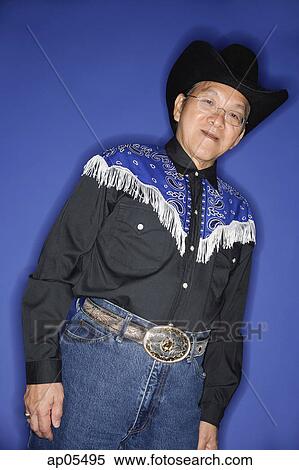 Senior man dressed in cowboy attire, standing against blue background View Large Photo Image Stock Photography - Senior man dressed in cowboy attire, standing against blue background. Fotosearch