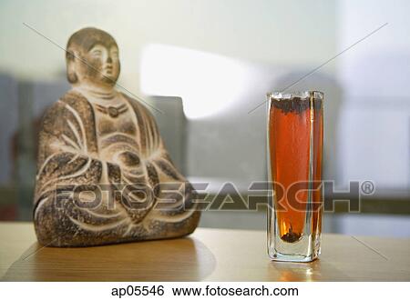 Still life with glass of tea and Buddha icon View Large Photo Image Stock Photograph - Still life with glass of tea and Buddha icon. Fotosearch