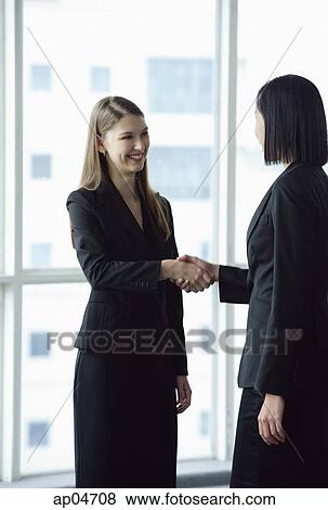 Two businesswomen standing and shaking hands View Large Photo Image Stock Photo - Two businesswomen standing and shaking hands. Fotosearch