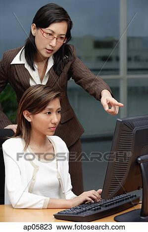 Two businesswomen working together, looking at computer View Large Photo Image Stock Image - Two businesswomen working together, looking at computer. Fotosearch