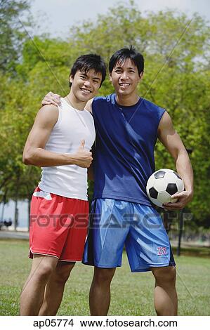 Two men looking at camera, one holding soccer ball View Large Photo Image Picture - Two men looking at camera, one holding soccer ball. Fotosearch