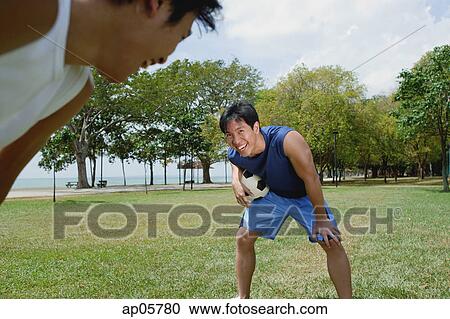 Stock Image - Two men on field, one holding soccer ball. Fotosearch