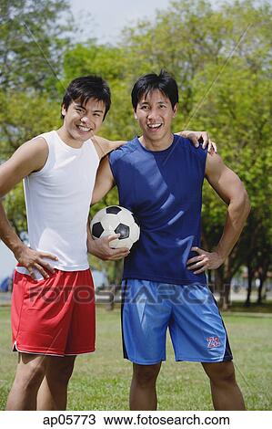 Two men standing together, one holding soccer ball View Large Photo Image Stock Image - Two men standing together, one holding soccer ball. Fotosearch