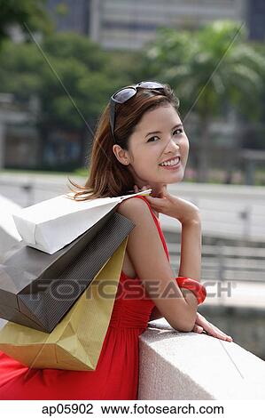 Woman carrying shopping bags over shoulder, leaning on railing View Large Photo Image Stock Image - Woman carrying shopping bags over shoulder, leaning on railing. Fotosearch