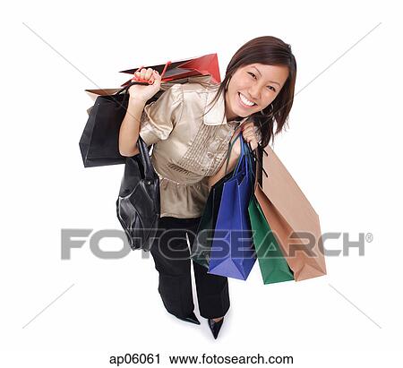 Woman carrying shopping bags, smiling up at camera View Large Photo Image Stock Image - Woman carrying shopping bags, smiling up at camera. Fotosearch