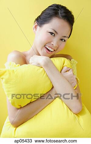 Stock Image - Woman embracing pillow, smiling at camera. Fotosearch