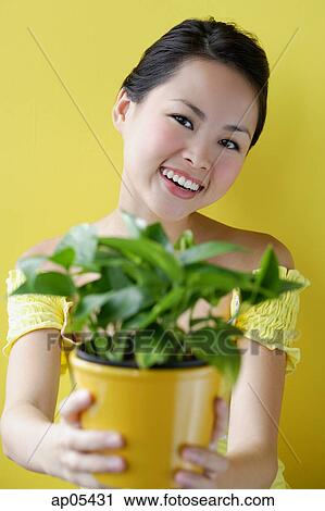 Woman holding house plant, smiling View Large Photo Image Stock Image - Woman holding house plant, smiling. Fotosearch