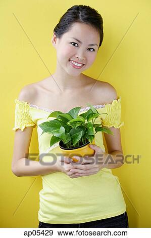 Stock Photo - Woman holding house plant. Fotosearch