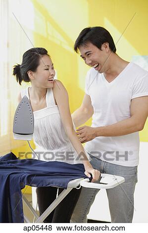 Woman holding iron, man tickling her View Large Photo Image Stock Photo - Woman holding iron, man tickling her. Fotosearch