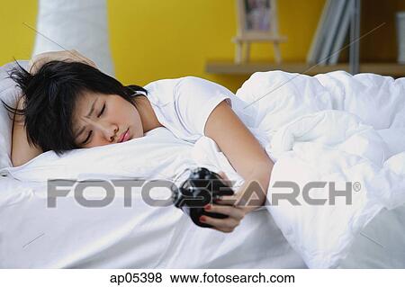 Woman in bed, looking at alarm clock, frowning View Large Photo Image Stock Photo - Woman in bed, looking at alarm clock, frowning. Fotosearch