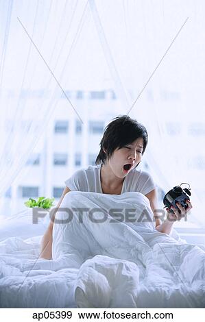 Woman in bed, looking at alarm clock, mouth open View Large Photo Image Stock Photo - Woman in bed, looking at alarm clock, mouth open. Fotosearch