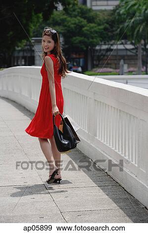 Woman in red dress carrying shopping bags, looking over shoulder View Large Photo Image Stock Photo - Woman in red dress carrying shopping bags, looking over shoulder. Fotosearch