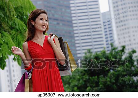 Woman in red dress carrying shopping bags, city location View Large Photo Image Stock Photo - Woman in red dress carrying shopping bags, city location. Fotosearch