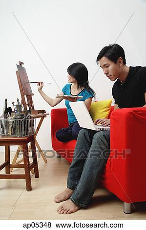 Woman painting on easel, man using laptop View Large Photo Image Stock Photo - Woman painting on easel, man using laptop. Fotosearch