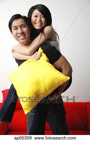 Stock Photo - Woman riding piggyback on man, smiling at camera. Fotosearch