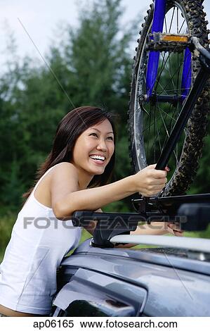 Woman securing bike on top of car View Large Photo Image Stock Photography - Woman securing bike on top of car. Fotosearch