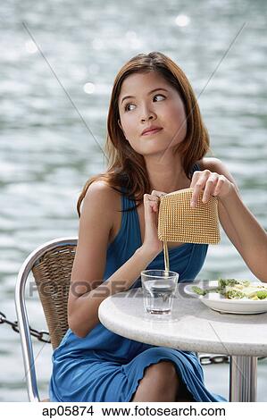 Woman sitting at table in cafe, holding her purse View Large Photo Image Picture - Woman sitting at table in cafe, holding her purse. Fotosearch
