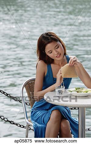 Woman sitting at table in cafe, looking through her purse View Large Photo Image Stock Photography - Woman sitting at table in cafe, looking through her purse. Fotosearch