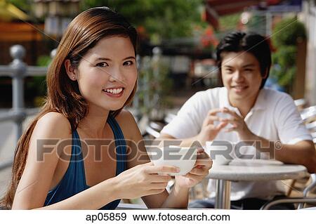 Stock Photo - Woman sitting in cafe, having coffee, man in the background. Fotosearch