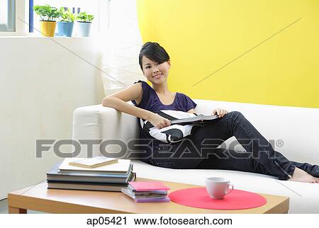 Woman sitting on sofa, looking at camera View Large Photo Image Stock Image - Woman sitting on sofa, looking at camera. Fotosearch