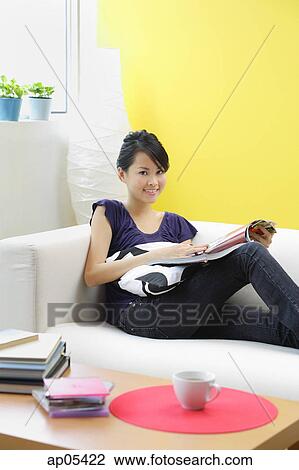 Woman sitting on sofa, looking at camera View Large Photo Image Stock Image - Woman sitting on sofa, looking at camera. Fotosearch