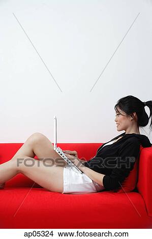 Woman sitting on sofa with laptop View Large Photo Image Picture - Woman sitting on sofa with laptop. Fotosearch