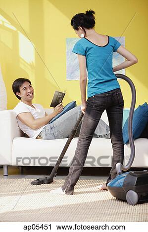 Woman vacuuming, man sitting on sofa with book, smiling at her View Large Photo Image Stock Image - Woman vacuuming, man sitting on sofa with book, smiling at her. Fotosearch