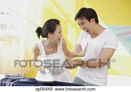 Stock Photo - Woman with iron pushing man away. Fotosearch
