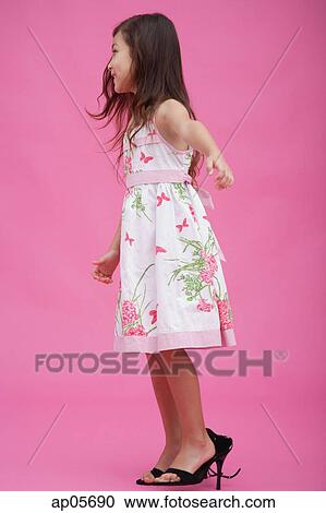 Stock Image - Young girl wearing high heel shoes, side view. Fotosearch