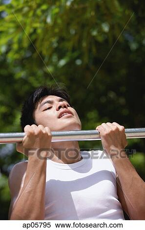 Young man using chin-up bar View Large Photo Image Stock Photography - Young man using chin-up bar. Fotosearch