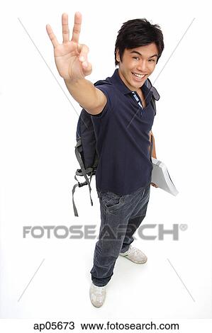 Young man with books and a backpack, making hand sign View Large Photo Image Stock Image - Young man with books and a backpack, making hand sign. Fotosearch