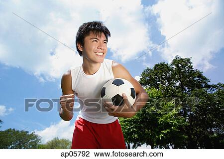 Young man with soccer ball, hand in a fist, smiling View Large Photo Image Stock Image - Young man with soccer ball, hand in a fist, smiling. Fotosearch