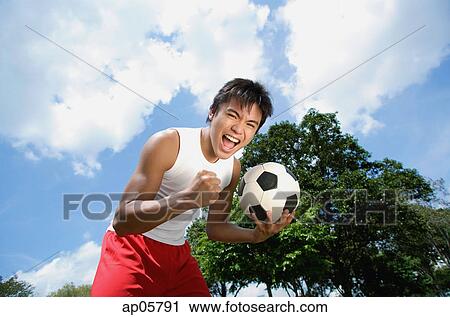 Young man with soccer ball, looking at camera, hand in a fist View Large Photo Image Stock Image - Young man with soccer ball, looking at camera, hand in a fist. Fotosearch