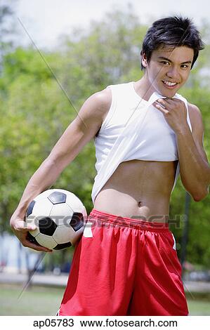 Young man with soccer ball, wiping chin with T shirt View Large Photo Image Stock Image - Young man with soccer ball, wiping chin with T shirt. Fotosearch