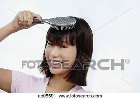 Young woman brushing her hair, smiling at camera View Large Photo Image Stock Image - Young woman brushing her hair, smiling at camera. Fotosearch