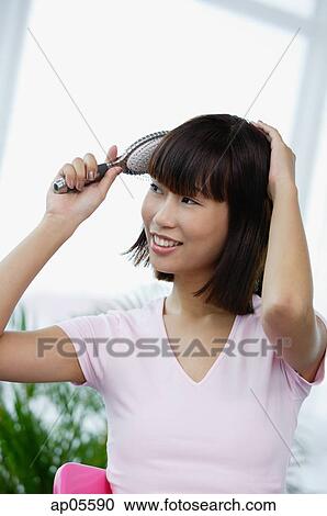 Stock Image - Young woman brushing her hair. Fotosearch
