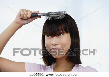 Stock Image - Young woman brushing her hair. Fotosearch
