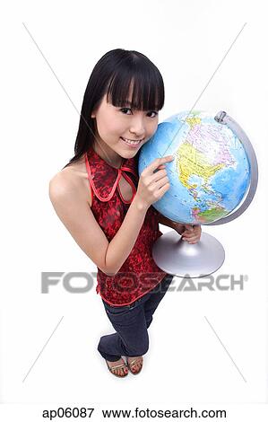 Young woman holding and pointing at globe View Large Photo Image Stock Photo - Young woman holding and pointing at globe. Fotosearch