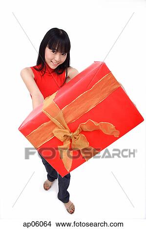 Young woman holding big red gift box towards camera View Large Photo Image Picture - Young woman holding big red gift box towards camera. Fotosearch