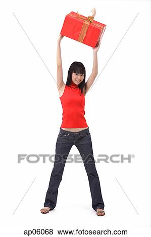 Young woman holding big red gift box over her head View Large Photo Image Stock Photo - Young woman holding big red gift box over her head. Fotosearch