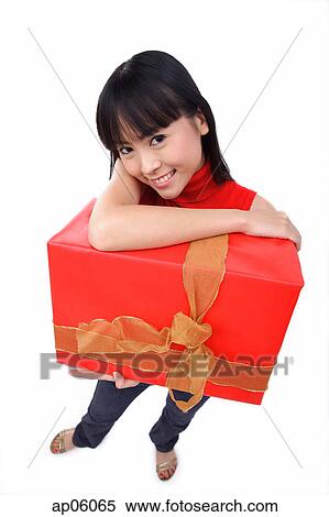 Stock Photography - Young woman holding big red gift box, portrait. Fotosearch
