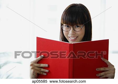 Young woman holding book, smiling at camera View Large Photo Image Stock Photography - Young woman holding book, smiling at camera. Fotosearch