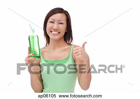 Stock Photography - Young woman holding bottled drink, making thumbs up sign. Fotosearch