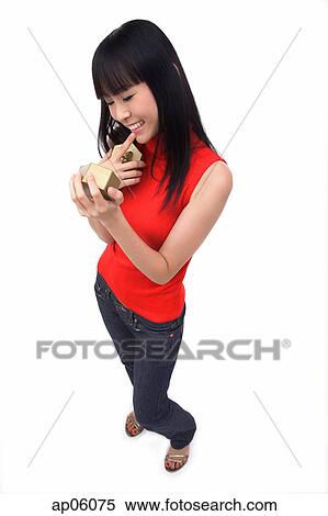Stock Photography - Young woman holding gift box, finger on mouth. Fotosearch