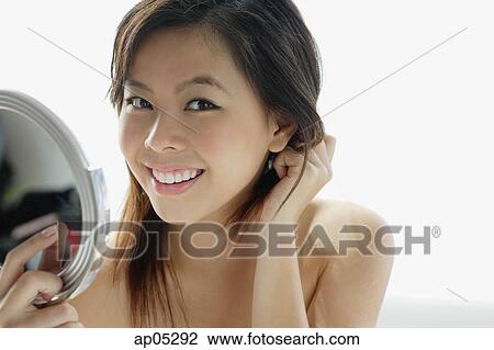 Young woman holding mirror, smiling at camera View Large Photo Image Stock Image - Young woman holding mirror, smiling at camera. Fotosearch
